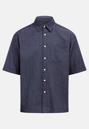 Μπλε πουκάμισο με κοντά μανίκια, κουμπιά μπροστά και λευκό πλέγμα μοτίβο, με τσέπη στο στήθος, εμφανιζόμενο σε απλό ανοιχτό γκρι φόντο.