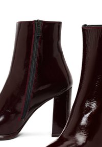 Stivaletti alla caviglia in vera pelle bordeaux con tacco a blocco alto, dotati di chiusura con zip laterale e dettagli di cucitura rossa a contrasto.