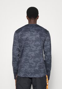 Koszula z długim rękawem w ciemnoniebieskim kolorze z pikselowym wzorem kamuflażu, wykonana z gładkiego, lekkiego materiału, z okrągłym dekoltem.