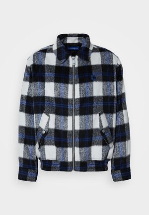 Fleece-takki musta-valko-harmaassa ruutukuosisessa sinisillä korostuksilla. Takissa on edessä vetoketju ja sivutaskut sekä kaulus.