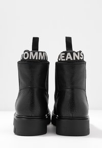 Czarne skórzane botki za kostkę o teksturowanym wykończeniu, z masywną podeszwą i wyściełanym kołnierzem z białym napisem "TOMMY JEANS".