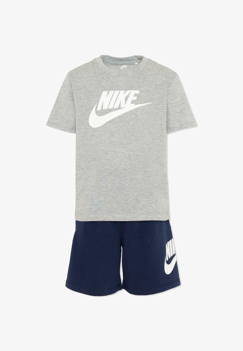 T-shirt gris à manches courtes de Nike avec logo blanc, associé à un short bleu marine de Nike portant un logo blanc sur la jambe gauche.