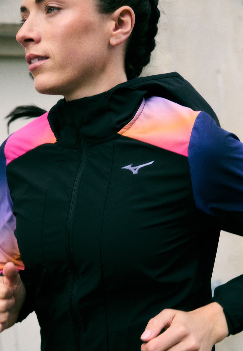 Black athletic jacket with a zip front. Features vibrant gradient accents in pink, orange, and blue on shoulders. Logo on the left chest.