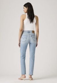 Lichtblauwe denim jeans met rechte pijpen, een hoge taille en kenmerkende achterzakken met een gebogen naadontwerp. Bruin leren merklabel.