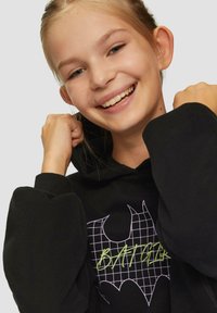 Zwarte hoodie met een groot vleermuislogo met een rasterpatroon. Het ontwerp bevat groene borduursels van het woord "BATGIRL." Zacht, textuurgegeven stof.