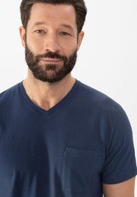 T-shirt en coton bleu marine à col en V, avec une poche poitrine et des manches courtes, présentant une texture lisse.