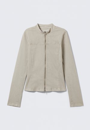 Μπεζ μακρυμάνικο σακάκι με μπροστινό φερμουάρ, στρογγυλή γιακά και εμφανείς ραφές, απλωμένο επίπεδα σε ανοιχτό φόντο.