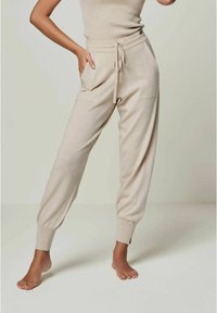Beige Jogginghose aus weichem Stoff, mit elastischem Bund, Kordelzug, Seitentaschen und schmalen Bündchen.