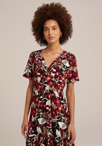 Blumenmusterkleid mit V-Ausschnitt, kurzen Ärmeln, taillierter Taille und gestuften Saum. Verziert mit roten, grünen und weißen Mustern auf schwarzem Hintergrund.