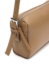Borsa a tracolla rettangolare beige in pelle con zip argentata, tracolla coordinata in pelle e fibbia argentata su sfondo bianco.