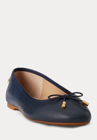 Ballerine en cuir bleu marine à bout arrondi, petit nœud avec embouts dorés et semelle en caoutchouc marron clair vue en angle trois quarts.