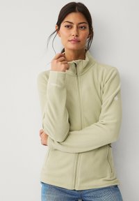 Giacca in pile verde chiaro con colletto alto, zip completa e maniche lunghe. Presenta un logo sottile sulla spalla e una trama morbida.