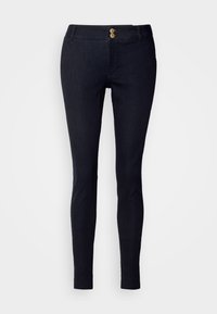 Pantalon slim bleu marine avec fermeture à double bouton doré et passants de ceinture, présenté sur un fond clair uni.