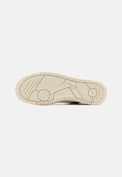 Sneaker zole, kas izgatavota no teksturēta, gaiši bežā gumijas materiāla, ar izteiktiem iegriezumiem un apļa dizaina elementu ar uzrakstu "Polo".