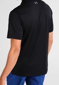 Polo noir avec un design texturé, manches courtes et col. Détail notable d'un logo à l'arrière du col.