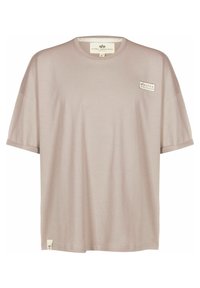 T-shirt beige a maniche corte con collo rotondo, piccolo logo "Alpha Industries" sul petto e etichetta sull'orlo inferiore.