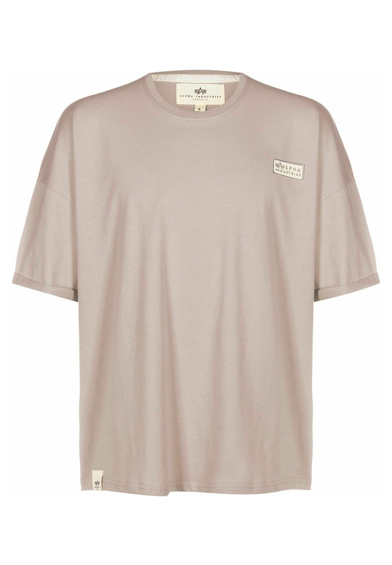 T-shirt beige a maniche corte con collo rotondo, piccolo logo "Alpha Industries" sul petto e etichetta sull'orlo inferiore.