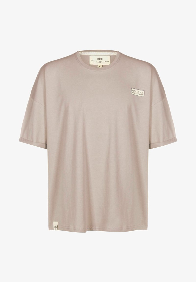 T-shirt beige a maniche corte con collo rotondo, piccolo logo "Alpha Industries" sul petto e etichetta sull'orlo inferiore.
