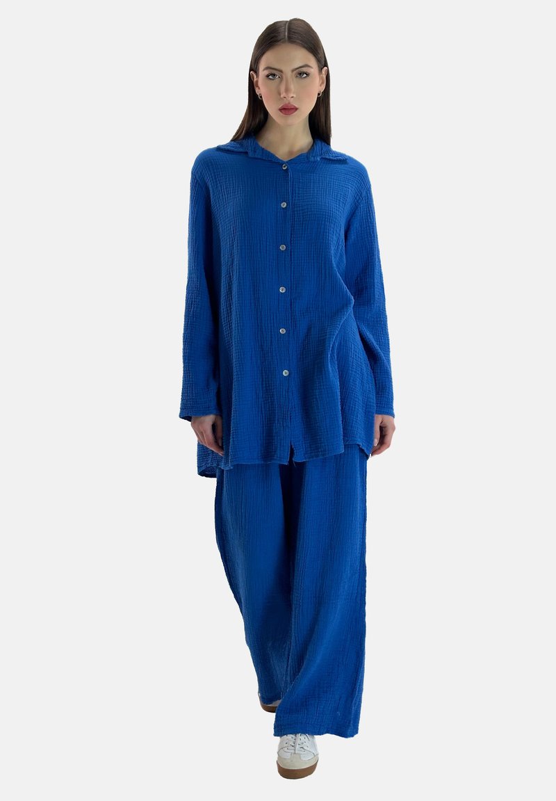 Camisa azul de botón con textura y cuello, combinada con pantalones azul sueltos. Ambos artículos cuentan con un diseño de tela arrugada.