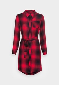 Punainen ja musta ruudullinen mekko, pitkähiha, nappikiinnitys, kaulus, rintatasku, mukana tuleva kangasvyö ja pyöristetty helma. Flanellikangas.