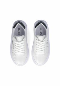 Baskets blanches avec une texture lisse, accents noirs contrastants au niveau du talon, et lacets blancs plats. Logo imprimé sur la languette.