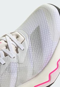 Buty sportowe z białą siateczką na górze, z teksturowanym wzorem, jasnoszarymi akcentami, kremową podeszwą środkową i jaskraworóżową podstawą podeszwy.