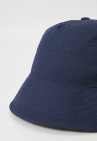 Chapeau seau bleu marine en tissu léger, avec un large bord et des coutures le long de la couronne et des bords.