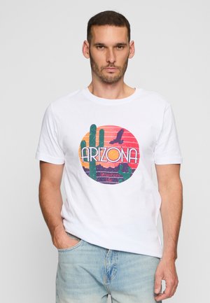 Hvid bomulds t-shirt med et cirkulært grafik af kaktusser, bjerge og teksten "ARIZONA American Life" i livlige farver.