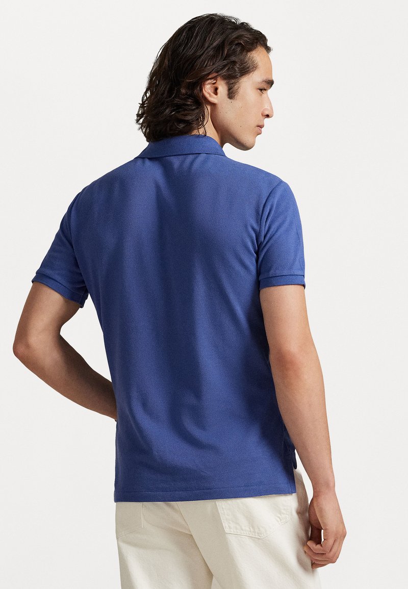 Korte mouwen polo shirt in een effen diepblauwe kleur met een gestructureerde breisel. Voorzien van een standaard kraag en een comfortabele pasvorm, gecombineerd met lichtgekleurde broeken.