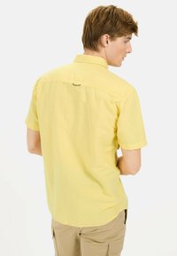Kortekleurig geel shirt, lichtgewicht stof, met knoopsluiting, gebogen zoom, met een klein logodetail op de achterste yoke.