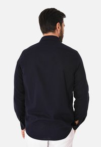 Camicia a maniche lunghe blu navy con colletto button-down, vestibilità casual e dettagli sulla patta. Realizzata in un morbido tessuto misto cotone.