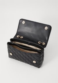 Gequiltete schwarze Lederhandtasche mit goldenen Beschlägen, ausgestattet mit zwei Fächern und einem Druckknopfverschluss. Das Innere hat ein markenbezeichnetes Futter.