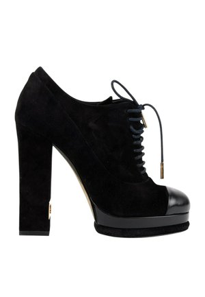 Chaussure à talon haut en daim noir avec semelle plateforme, bout en cuir noir et lacets noirs avec embouts dorés, vue de profil.