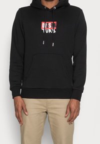 Svart huvtröja med en framficka och snörning. Har vit och röd grafisk text på bröstet. Mjukt, texturerat tyg med ribbade muddar.