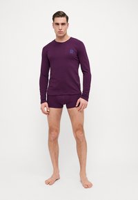 Vijolična dolgi rokavi majica in ujemajoči boxer kratke hlače iz mehkega blaga, z okroglim ovratnikom in majhnim logotipom na prsih.