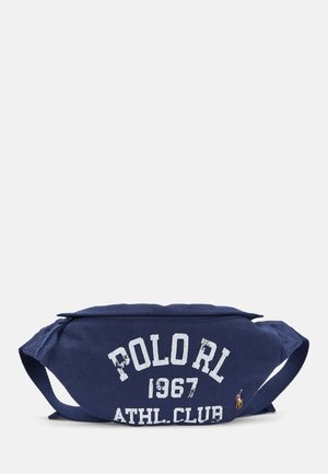 Sac banane en toile marine avec du texte blanc usé : "POLOrl 1967 ATHL. CLUB." Il comporte deux sangles et un petit logo sur un côté.