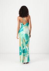 Robe longue et fluide avec un motif tie-dye vibrant vert et bleu. Elle présente des bretelles spaghetti croisées ajustables et un dos ouvert.
