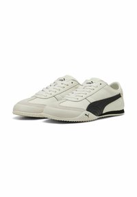 Zapatillas deportivas blancas y negras con upper de cuero y sintético, detalles texturizados, cierre de cordones y suela de goma con puntos de agarre.