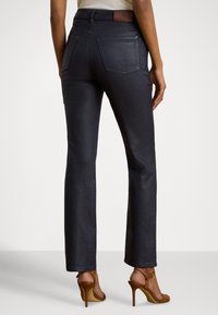 Tumši mazgātas džinsa bikses ar taisnu kāju griezumu, jostasvietā ar brūnu ādas plāksteri un divām aizmugures kabatām.