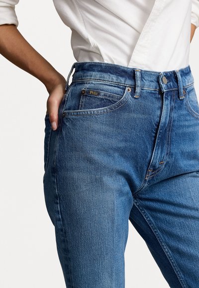 Hoge taille blauwe jeans met een gemiddelde was, voorzien van twee zijzakken, een logo label aan de achterkant en zichtbare stikdetails.