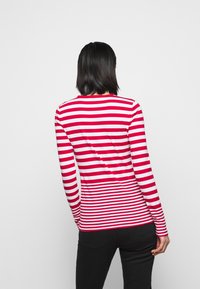 Koszula z długim rękawem w czerwono-białe paski, wykonana z miękkiego materiału, z okrągłym dekoltem i dopasowanym krojem.