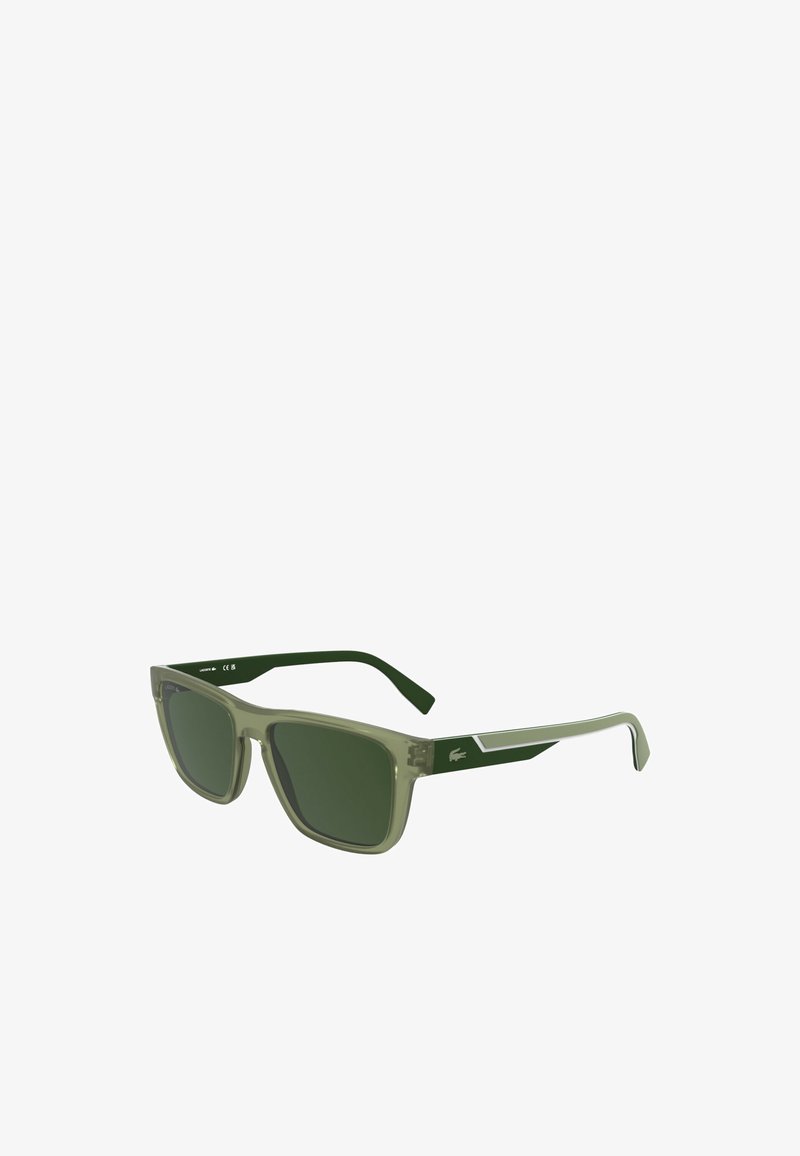 Prostokątne okulary przeciwsłoneczne z przezroczystymi oliwkowo-zielonymi oprawkami i ciemnozielonymi soczewkami. Metaliczne srebrne akcenty na zausznikach. Teksturalne ramiona.