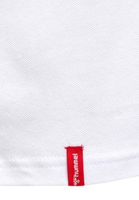 Hvid tekstureret stof med et rødt mærke, der viser mærket "hummel" nederst, med et enkelt og rent design.