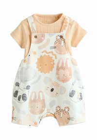 Chemise à manches courtes de couleur pêche associée �à des salopettes blanches ornées de motifs animaliers dans des teintes pastel douces et dotées de boutons en bois.