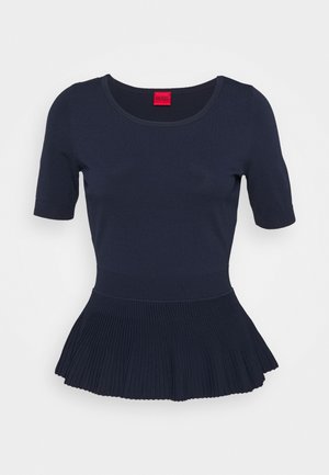 Granatowy top z krótkim rękawem, okrągłym dekoltem i plisowanym dołem peplum, z czerwoną metką wewnątrz kołnierzyka.