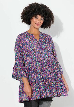 Tunique florale multicolore en violet, dotée d'un col en V, d'un ourlet festonné et de manches évasées. Le tissu semble léger avec un design fluide.