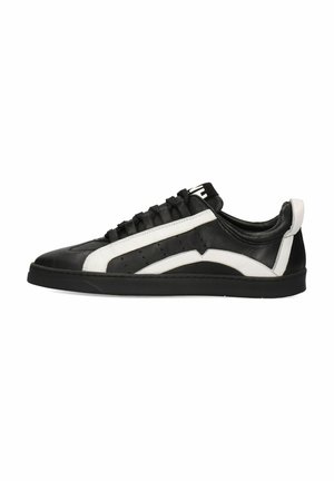 Zapatilla de cuero negro con acentos blancos, que presenta una textura suave, punta redondeada, perforaciones para transpirabilidad y suela plana de goma.