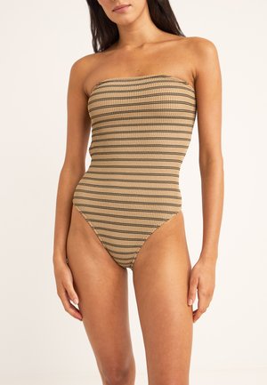 Bañador sin tirantes y de corte alto en una tela acanalada beige con finas rayas horizontales negras. La textura suave y el diseño ajustado realzan la figura.