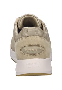 Beżowe zamszowe sneakersy z siateczkowego materiału, z wyściełanym kołnierzem i białą podeszwą. Charakteryzują się zaokrąglonym kształtem i wytłoczonym logo.