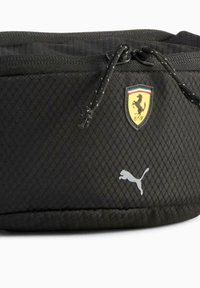 Pochette noire zippée en tissu texturé, présentant un logo Ferrari et un logo Puma blanc, avec une fermeture éclair à cordon.